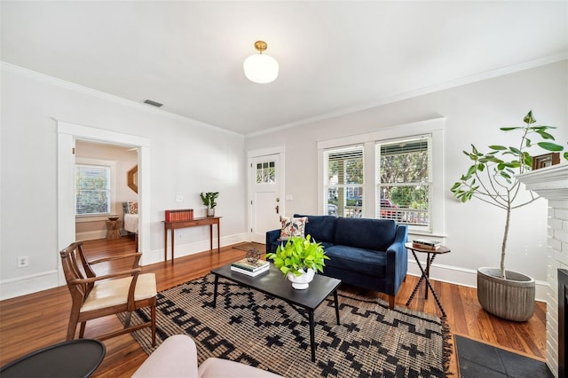 living room with visible vents, a healthy amount of sunlight, a brick fireplace, and wood finished floors