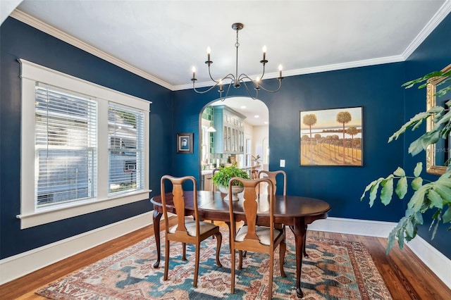 dining room featuring a chandelier, ornamental molding, baseboards, and wood finished floors