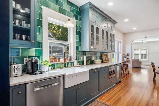 kitchen with a sink, light stone counters, stainless steel appliances, arched walkways, and decorative backsplash