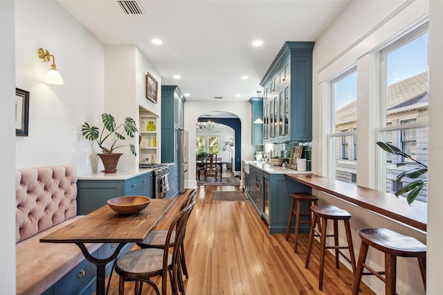 bar with visible vents, recessed lighting, arched walkways, appliances with stainless steel finishes, and light wood-type flooring