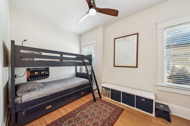 bedroom featuring baseboards, wood finished floors, and a ceiling fan