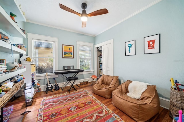 living room with ceiling fan, crown molding, baseboards, and wood finished floors