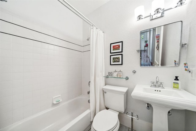 full bath featuring toilet, shower / tub combo with curtain, and a sink