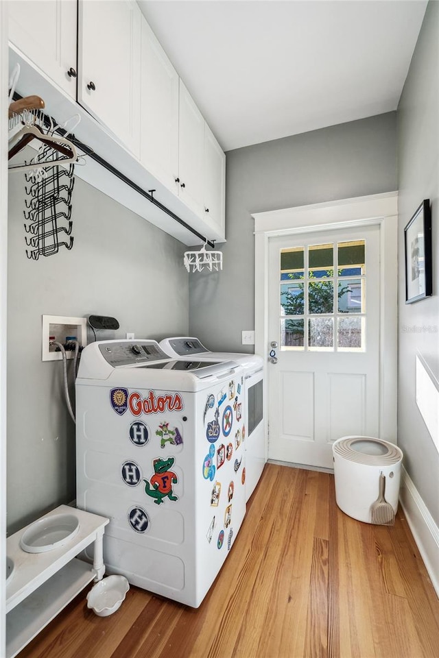 washroom featuring washing machine and dryer, cabinet space, and light wood-style flooring