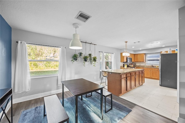 dining room with baseboards, visible vents, light wood-style flooring, and a textured ceiling