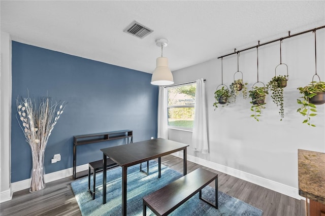 dining area featuring baseboards, visible vents, dark wood finished floors, and a textured ceiling