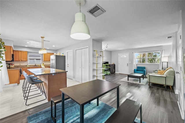 dining space with a textured ceiling, visible vents, and light wood-style floors