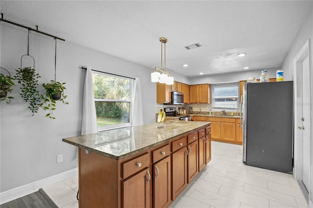 kitchen featuring visible vents, brown cabinetry, stainless steel appliances, stone counters, and recessed lighting