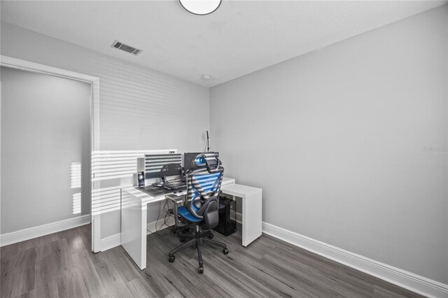 home office featuring visible vents, baseboards, and wood finished floors