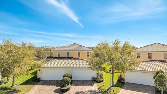 mediterranean / spanish house featuring driveway, stucco siding, a front yard, and a tiled roof