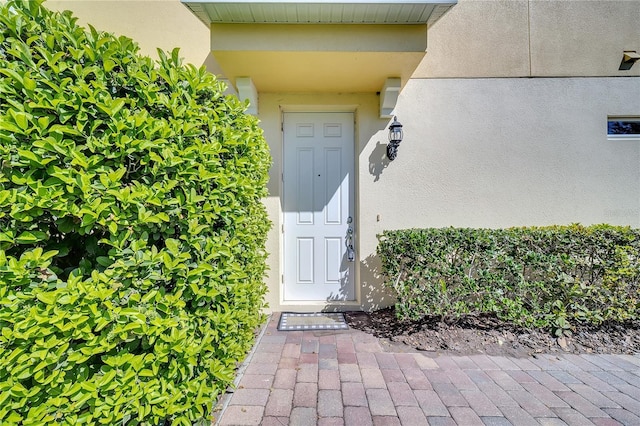 doorway to property featuring stucco siding