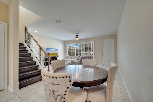 dining area with a ceiling fan, light tile patterned floors, baseboards, and stairs