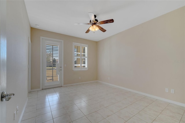 empty room with a ceiling fan, baseboards, and light tile patterned floors