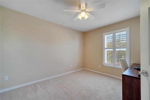 unfurnished office featuring baseboards, a ceiling fan, and light colored carpet