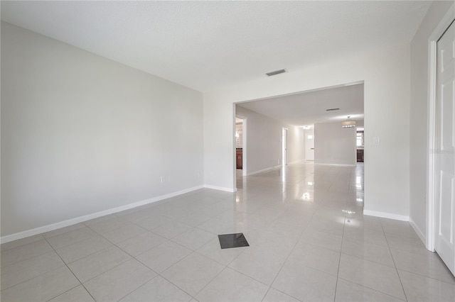 spare room with visible vents, baseboards, a textured ceiling, and light tile patterned flooring