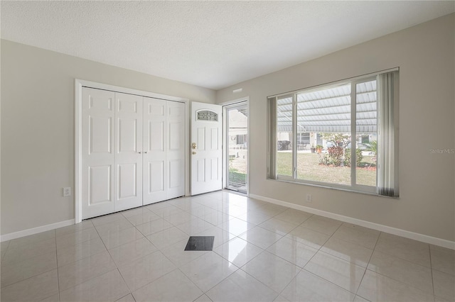 unfurnished bedroom featuring a textured ceiling, baseboards, light tile patterned flooring, and access to exterior