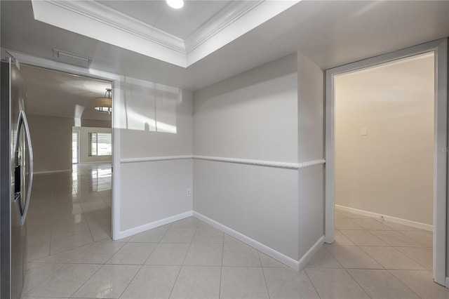 corridor featuring light tile patterned floors, visible vents, baseboards, a raised ceiling, and crown molding