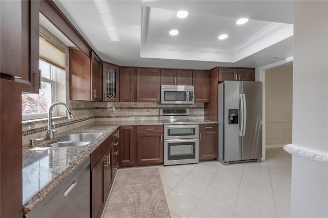 kitchen with decorative backsplash, a raised ceiling, appliances with stainless steel finishes, crown molding, and a sink