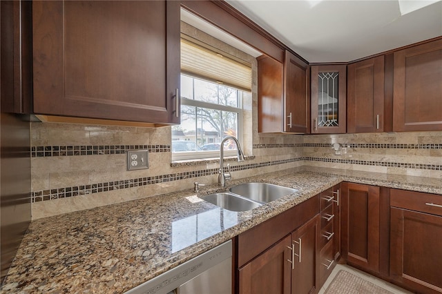 kitchen featuring tasteful backsplash, glass insert cabinets, a sink, and light stone counters