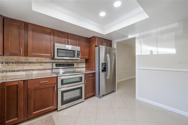 kitchen featuring decorative backsplash, light stone counters, ornamental molding, a tray ceiling, and stainless steel appliances