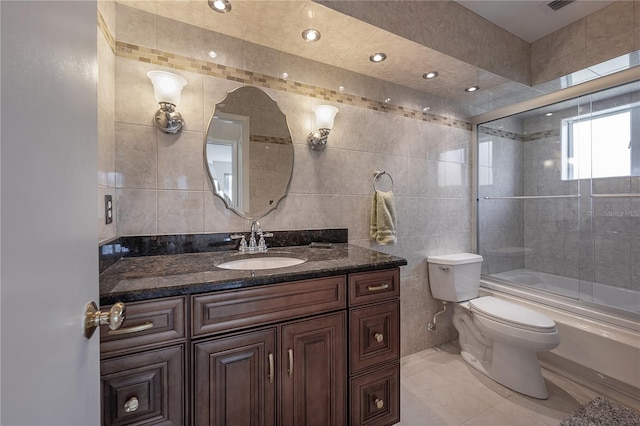 bathroom featuring toilet, vanity, tile walls, and enclosed tub / shower combo