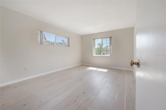 empty room with light wood-type flooring and baseboards