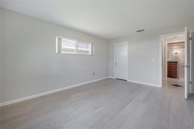 unfurnished bedroom with visible vents, light wood-style flooring, and baseboards