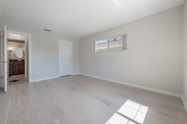 unfurnished bedroom with baseboards, visible vents, connected bathroom, and light wood finished floors