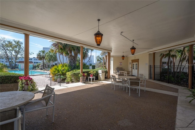 view of patio featuring outdoor dining area, french doors, a grill, fence, and a community pool