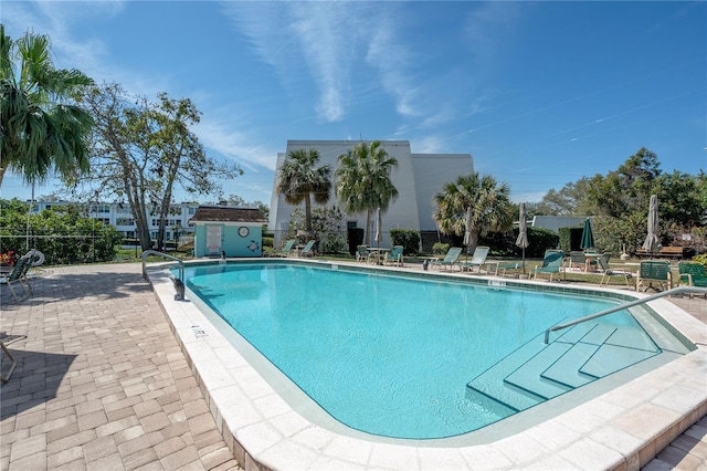 community pool with a patio area and an outdoor structure