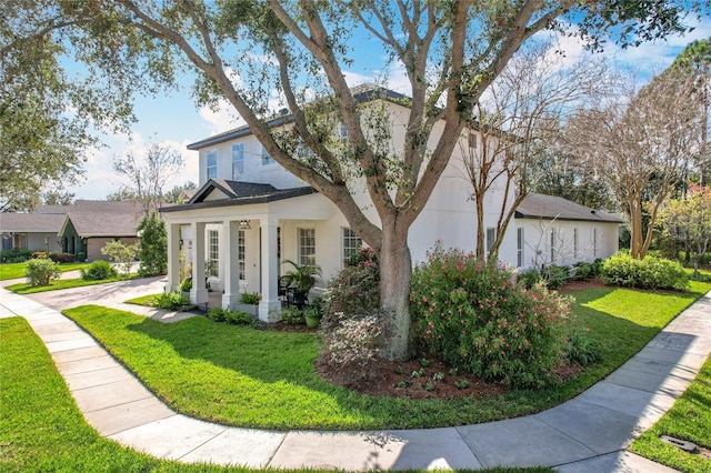 view of front of house featuring stucco siding, a porch, and a front yard