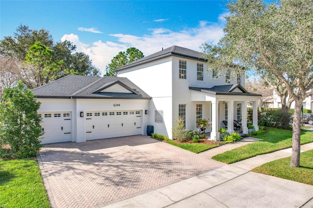 view of front of home with stucco siding, a porch, decorative driveway, and a garage