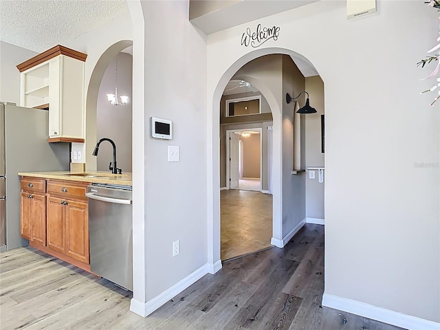 kitchen featuring light wood-style flooring, appliances with stainless steel finishes, open shelves, and light countertops