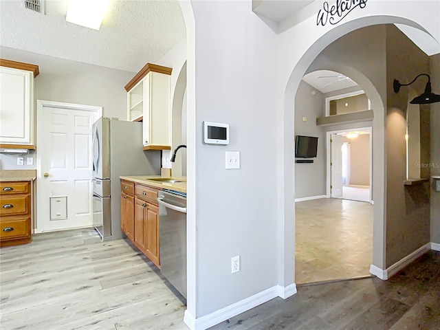 kitchen featuring dishwasher, light wood finished floors, a sink, and light countertops