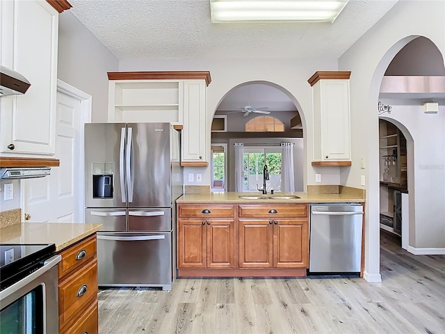 kitchen with light countertops, light wood-style flooring, appliances with stainless steel finishes, a sink, and a textured ceiling