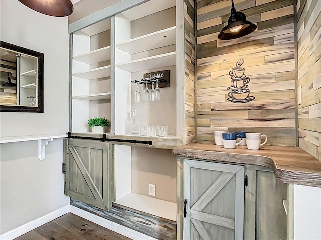 bar with dark wood finished floors, wood walls, and baseboards