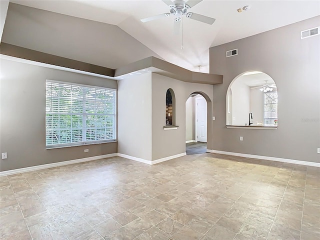 empty room with a ceiling fan, arched walkways, visible vents, and vaulted ceiling