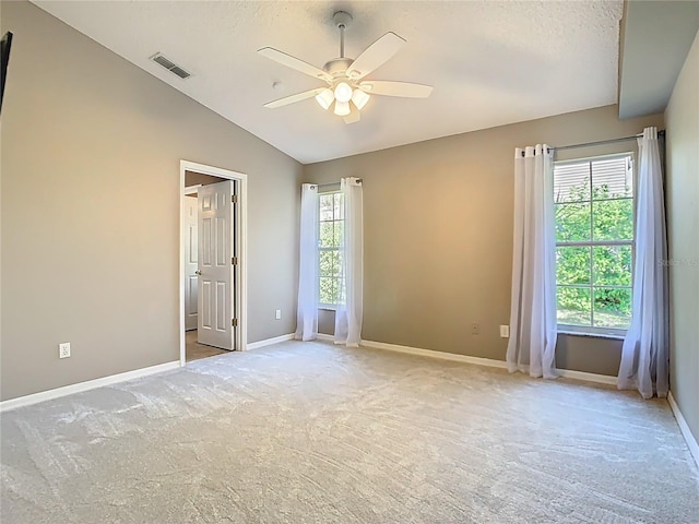 unfurnished room with lofted ceiling, light carpet, visible vents, and baseboards