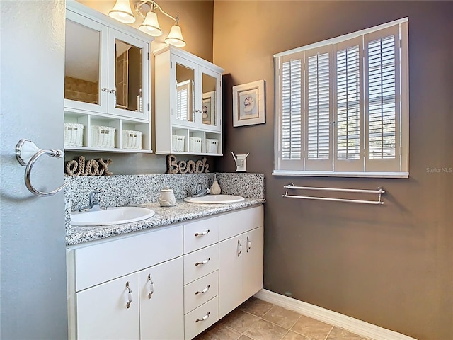 bathroom featuring double vanity, tile patterned flooring, baseboards, and a sink