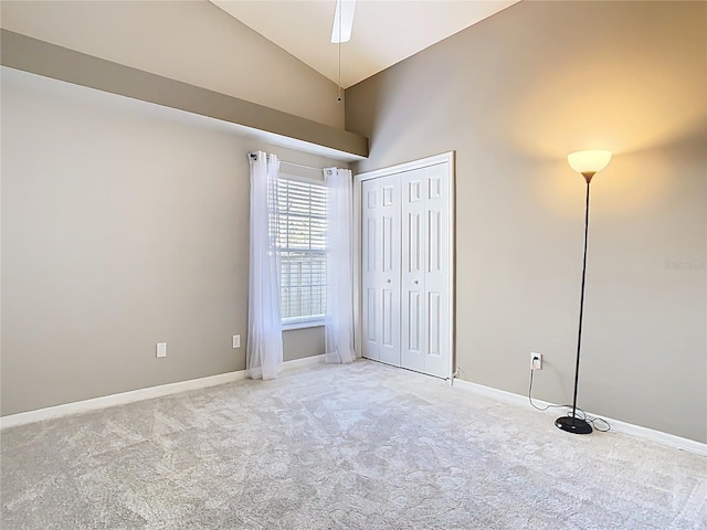 unfurnished bedroom featuring lofted ceiling, baseboards, a closet, and light colored carpet