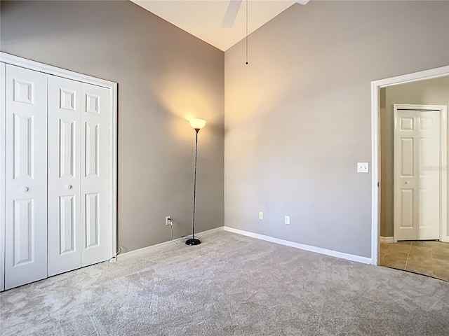 unfurnished bedroom featuring carpet, a closet, vaulted ceiling, ceiling fan, and baseboards