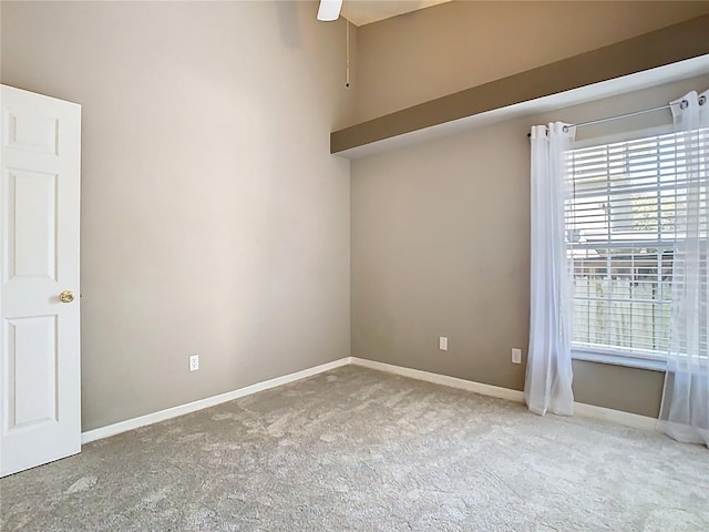 carpeted spare room featuring a ceiling fan and baseboards