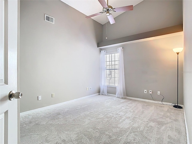 empty room with carpet floors, visible vents, a ceiling fan, high vaulted ceiling, and baseboards