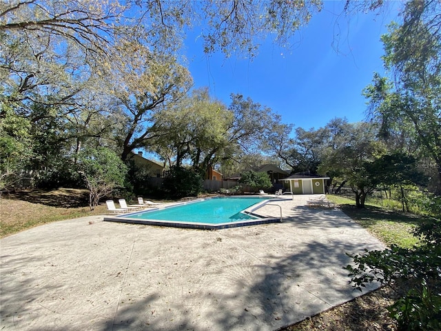 pool with an outbuilding, a patio area, and fence