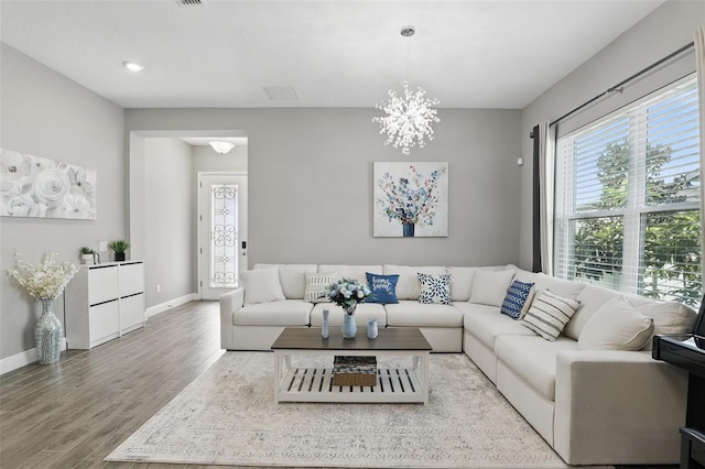 living area featuring an inviting chandelier, baseboards, and wood finished floors