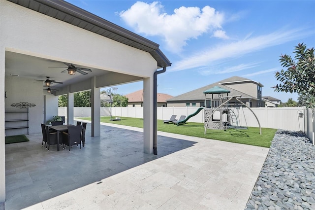 view of patio / terrace featuring outdoor dining area, a ceiling fan, a playground, and a fenced backyard