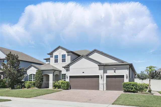 view of front of house featuring stucco siding, a front lawn, decorative driveway, stone siding, and fence