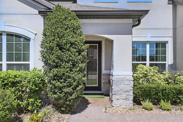 view of exterior entry with stone siding and stucco siding