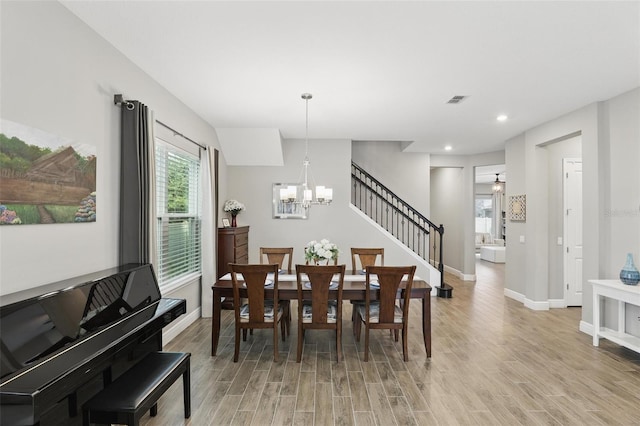 dining room featuring baseboards, a notable chandelier, light wood-style flooring, and stairs