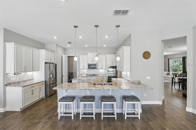 kitchen with visible vents, a peninsula, white cabinets, appliances with stainless steel finishes, and backsplash